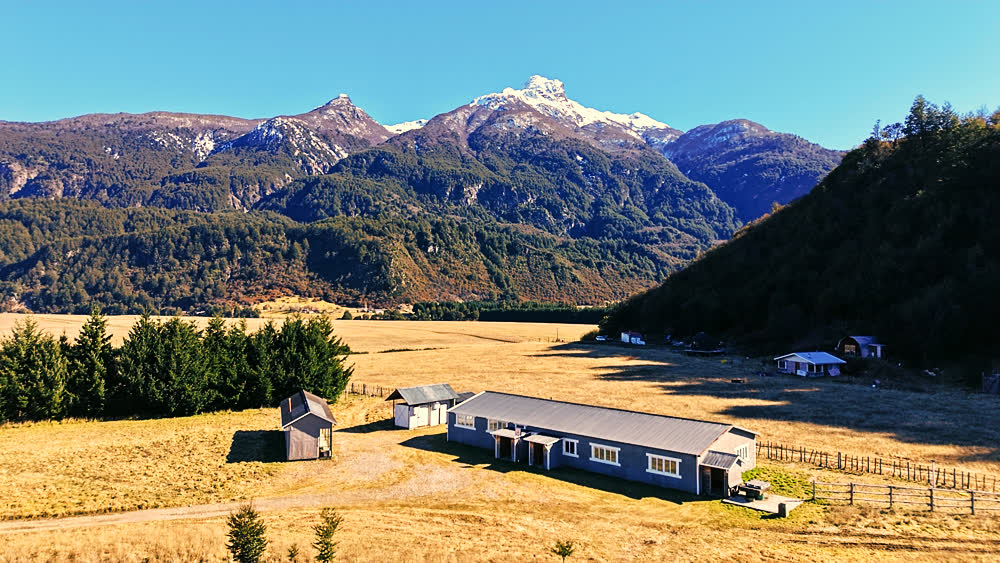 Vista aérea del galpón y bodegas del Fundo La Pampita, con la cordillera nevada de fondo